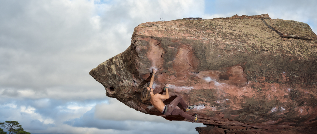 Man die een rotsblok beklimt in het Sierra de Albarracín-gebergte in Teruel, Aragón