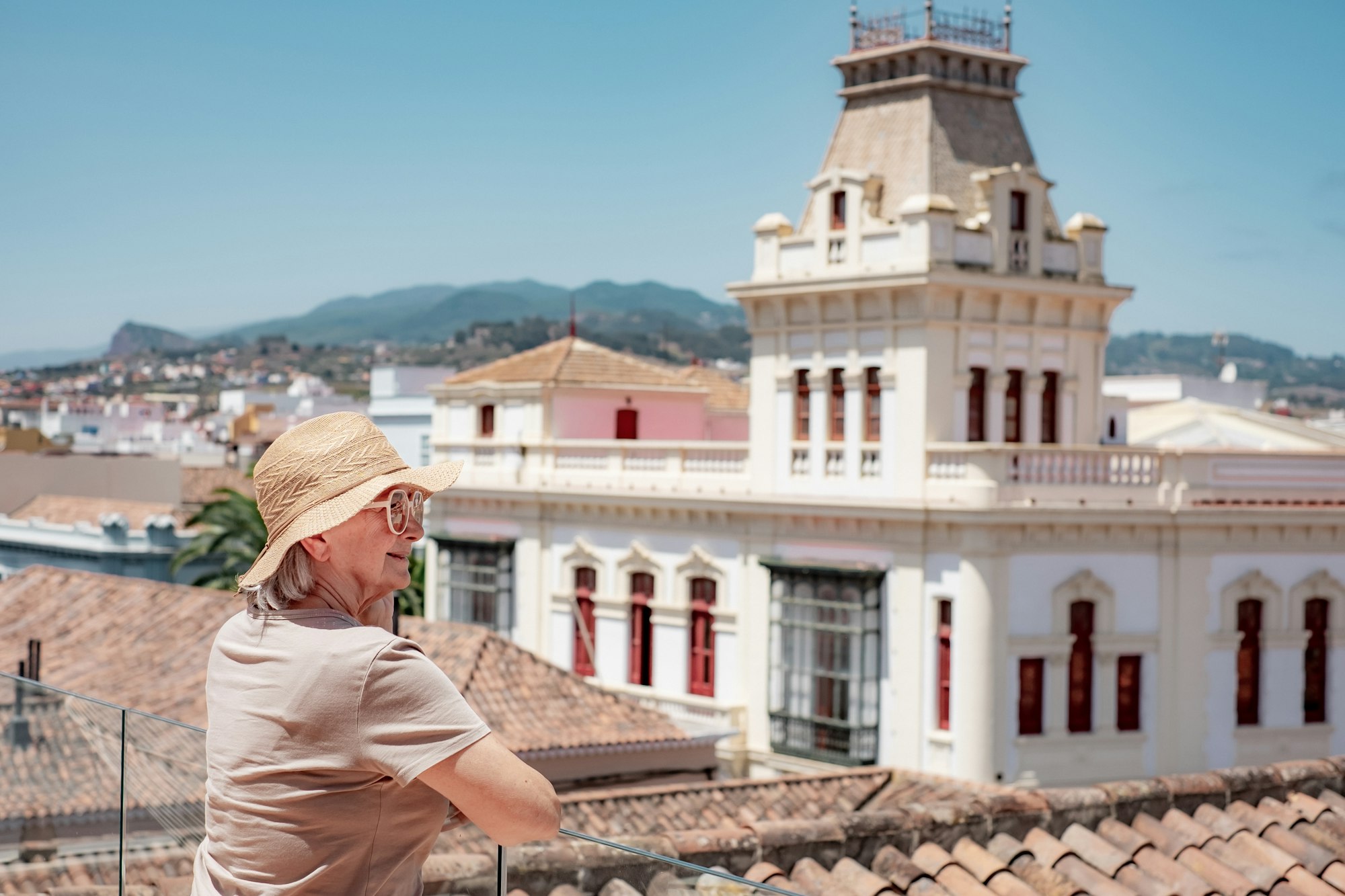 Happy traveler senior woman visiting La Laguna in Santa Cruz Tenerife admiring cityscape from roof